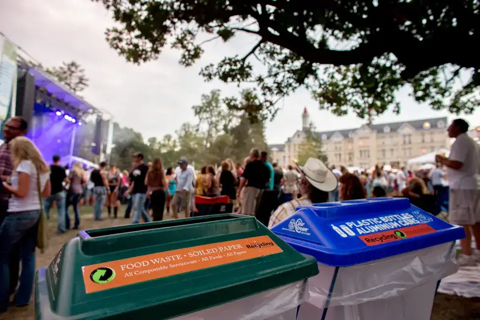 BARC compost and bottles-and-cans bins on a festival lawn at dusk