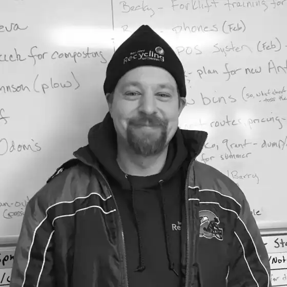 Black and white portrait of a crew member in a Recycling beanie in front of a whiteboard