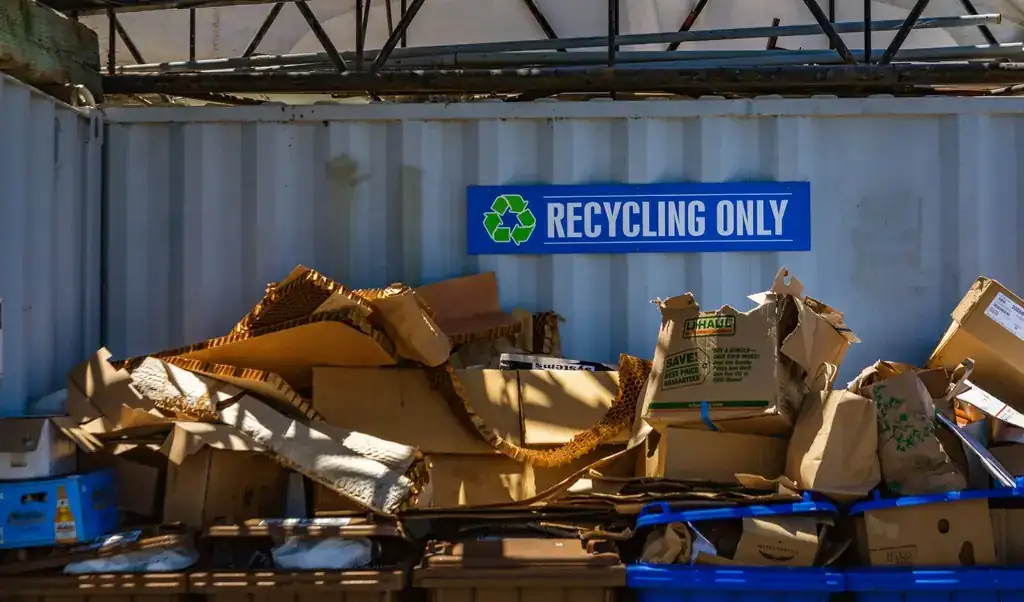 A heap of flattened cardboard under a blue RECYCLING ONLY sign