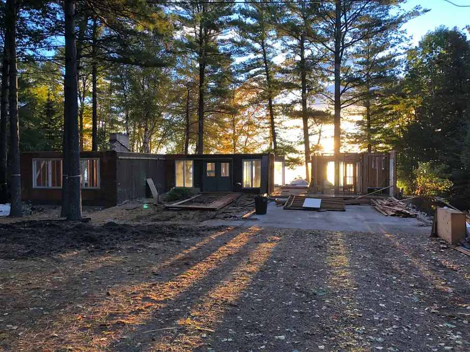 Deconstruction site at sunset with pines behind a partial house frame